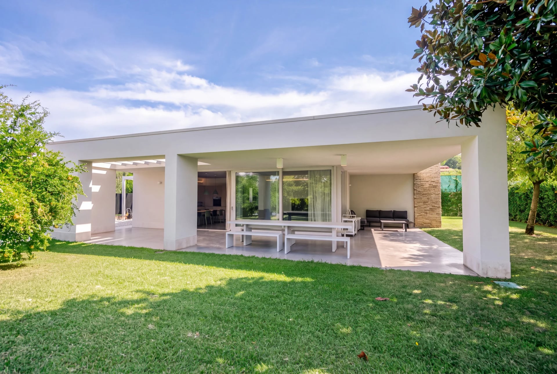 Villa bianca a un piano con ampio porticato, davanti un grande prato