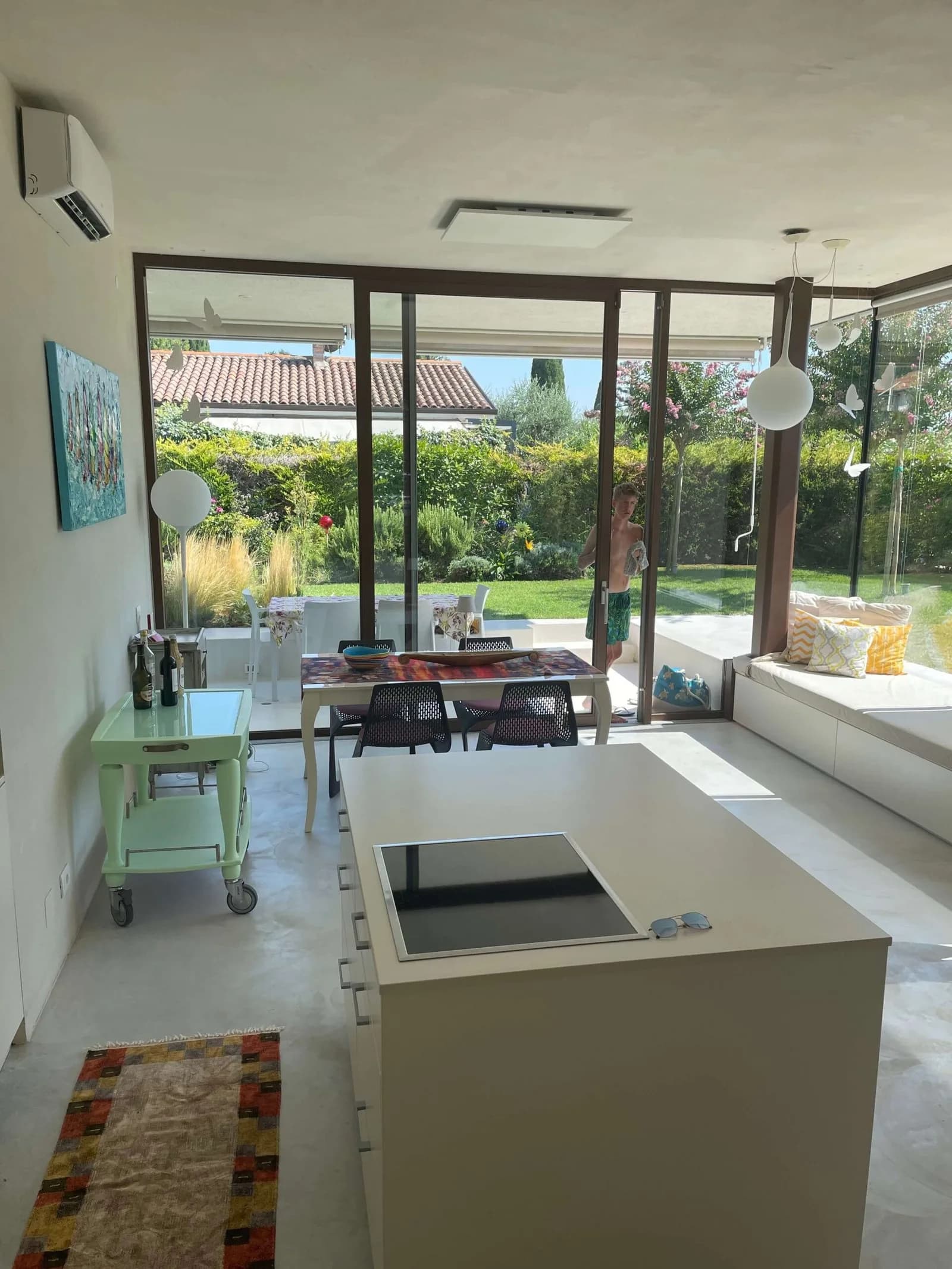 Kücheninsel im offenen Wohnraum, dahinter Glasfront mit Blick in den Garten
